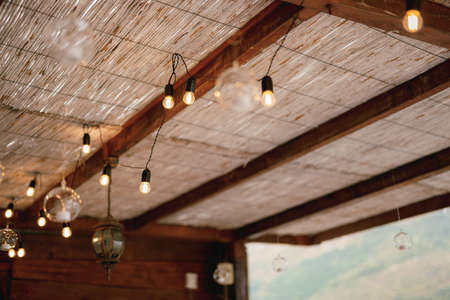 Garland on a wire of Led-light bulbs, under a thatched roof.の写真素材