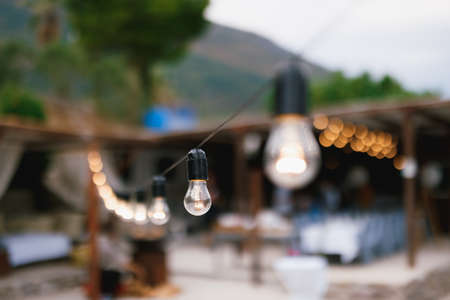 A close-up of an incandescent light bulb in a garland on the beach.の写真素材