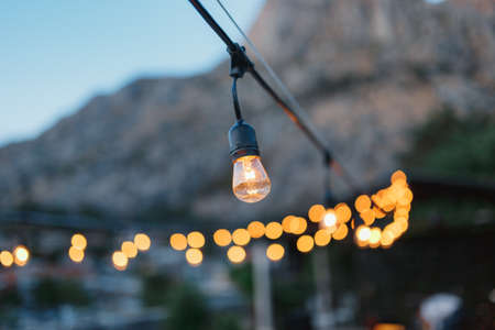 A garland of incandescent light bulbs, in the evening, against the backdrop of bokeh.の写真素材