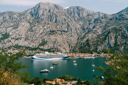 Cruise liner moored at the walls of the old town of Kotor, near a rocky mountain.の写真素材