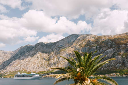 White cruise liner against the backdrop of rocky mountains. Moored ship near the cities of Dobrota...