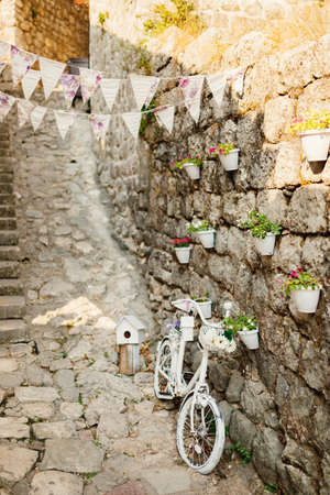 White decorative bike against the wall with pots for flowers and flags.の写真素材