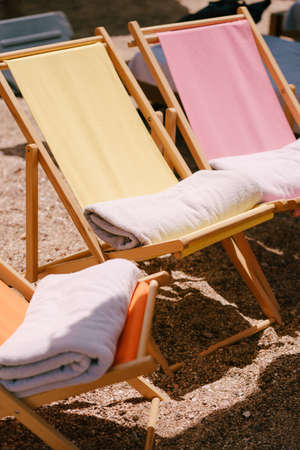 Wooden beach chairs, sun loungers and beach towels on the sandy beach.の写真素材