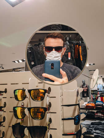 Budva, Montenegro - 01 august 2020: a man makes a selfie in the mirror on a smartphone, in a glasses store.のeditorial素材