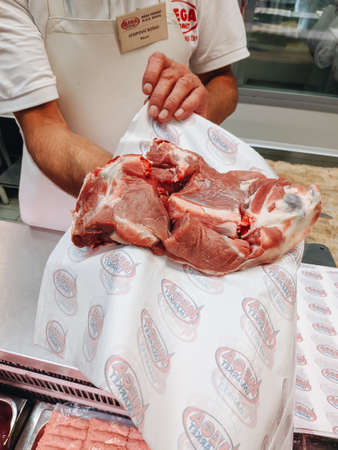 Budva, Montenegro - 01 august 2020: The butcher in the store shows meat.のeditorial素材