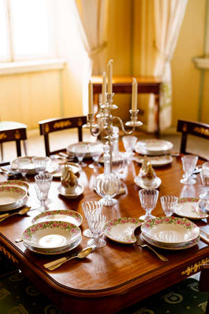 A festively decorated fish table with clean empty plates, spoons, knives, wine glasses, decanters...