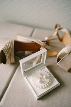 Mother-of-pearl womens sandals and a box with a bracelet of white beads and earrings.の写真素材