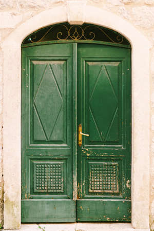 Closed doors of shabby green with a metal grille in the archの写真素材