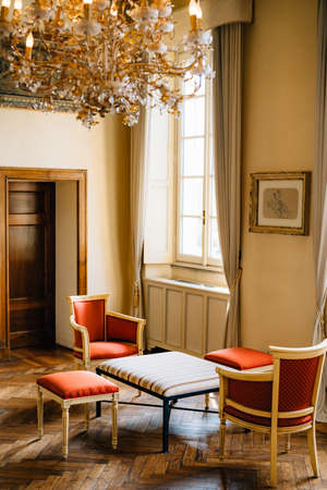 Bellagio, Italy - 07 june 2020: A coffee table with two armchairs and stools in a room with a window...