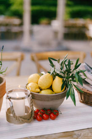 Deep plate with lemons on the table with a sprig of cherry tomatoes on a blurred background.の写真素材