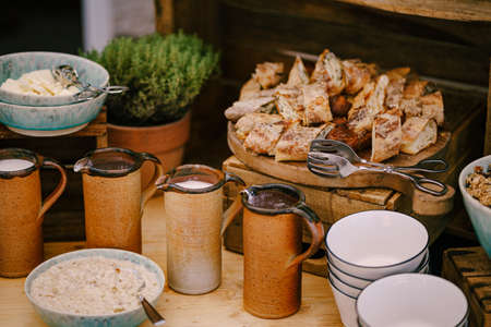 Copper mugs with milk and hot chocolate on the table by a plate with milk porridge and fresh...