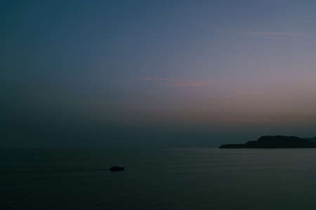 The boat sails into the sea at dusk against the sky after sunset.の写真素材