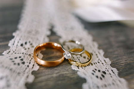 Close-up of gold wedding rings and white gold rings for the bride on white lace.の写真素材