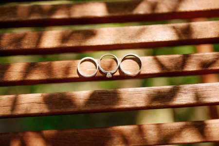 Gold wedding rings and an engagement ring on wooden tablets.の写真素材