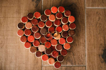 Wedding rings of the bride and groom on a pattern of hearts made of wine bottle corks on a wooden...