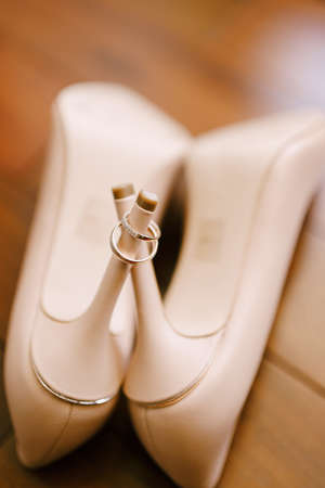 Wedding gold rings on heels of cream shoes on a blurred background.の写真素材