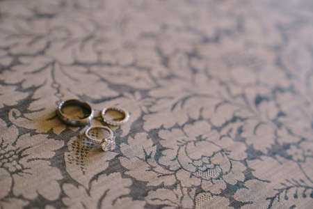 White gold wedding rings and bridal engagement ring with gem on blue fabric with white flowers.の写真素材