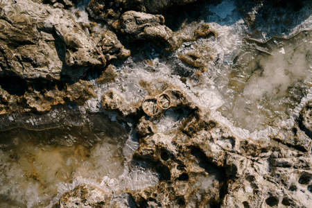 Two wedding rings on a stone structure in sea salt.の写真素材