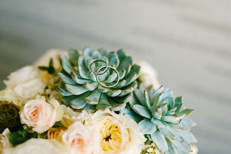 Wedding rings of the bride and groom on the echeveria flower in the brides wedding bouquet on a...