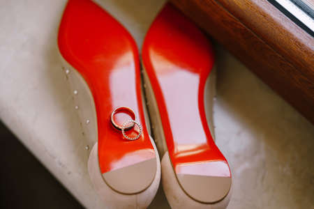 Wedding gold rings on the red sole of ballet shoes for the bride on the windowsill.の写真素材