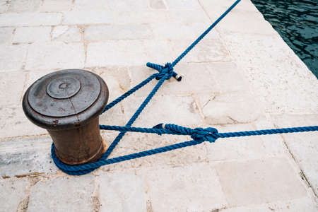The old metal maritime bollard with mooring ropes.