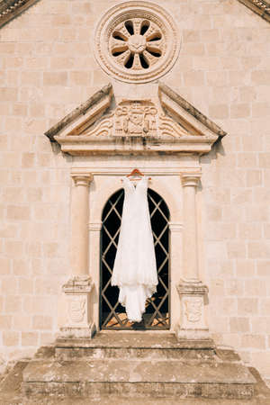 The wedding dress hangs at the entrance to the old church, between the columns, under the church rosette and bas-reliefs.の写真素材