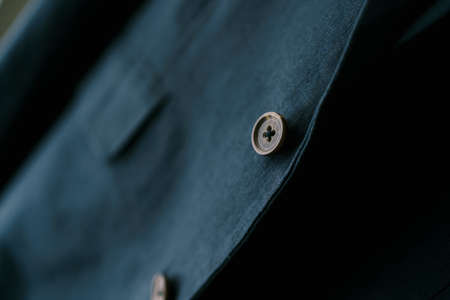 Close-up of a brown button on a navy blue mens blazer.