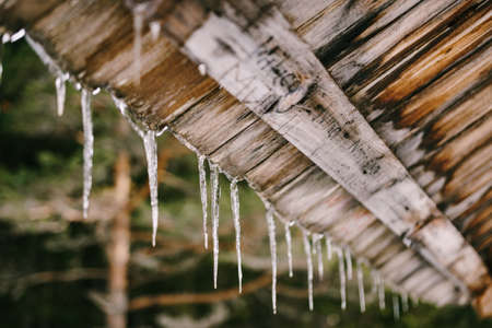 Icicles hang from a wooden roof in spring.