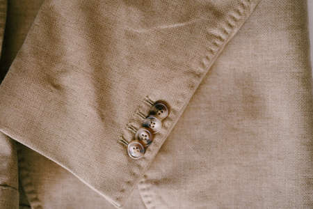 Beige mens blazer with buttons on the sleeve.