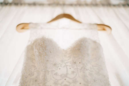 Close-up of a white corset of a bridesmaid dress with beads on a hanger, shallow depth of field.の写真素材