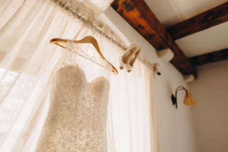 The brides dress and womens wedding shoes on the cornice by the window with a shallow depth of field.の写真素材