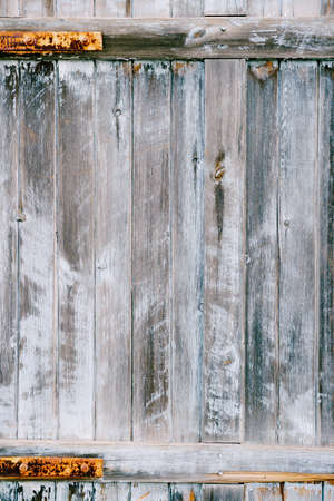 The texture of wooden planks is gray-blue. Close-up of a gray fence with rusty fittings.