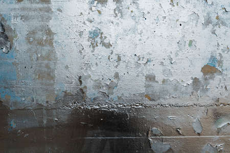A close-up of a gray concrete wall made of massive slabs with peeling paint.の写真素材