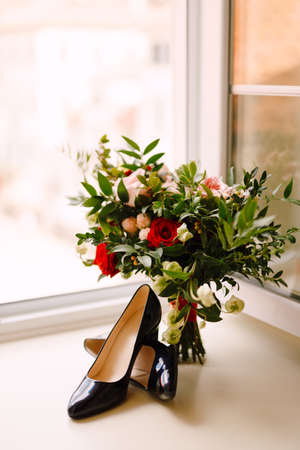Black shoes on a white windowsill with a bridal bouquet at the open window.の写真素材