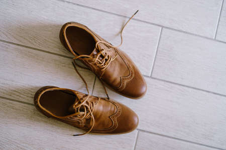 Brown mens shoes with untied laces on a white laminate.の写真素材