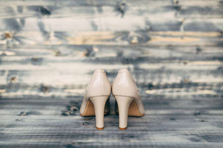 Beige high-heeled bridesmaid shoes on gray wooden texture.の写真素材