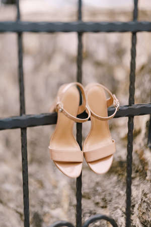Womens beige sandals on a metal fence with a shallow depth of field.の写真素材