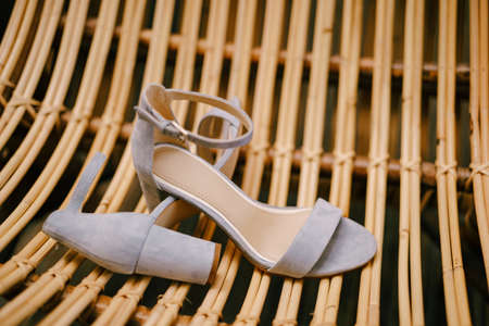 A chair made of wooden rods with womens sandals on the seat.の写真素材