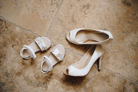 Womens white open toe shoes and little girls white sandals on the marble floor.の写真素材