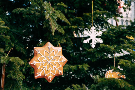 Wooden Christmas tree toys in the shape of an asterisk on the green branches of a Christmas tree.