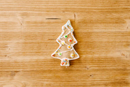 Gingerbread cookies in the shape of a Christmas tree decorated with powder on a light wooden...