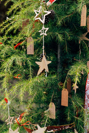 Wooden Christmas tree toys and notes on tree branches.