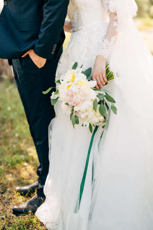 bride and groom standing together, bride is holding a bouquetの写真素材