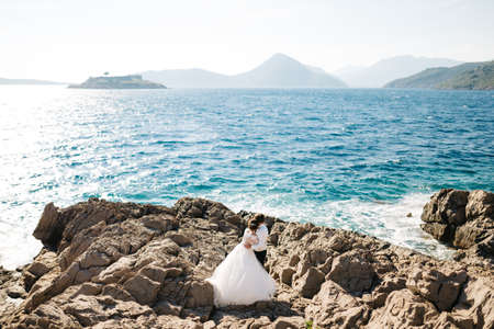 bride and groom are hugging on the rocky beach of the Mamula island near Arza fortressの写真素材