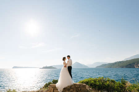 bride and groom are hugging on the beach of the Mamula island against the backdrop of the Arza fortressの写真素材