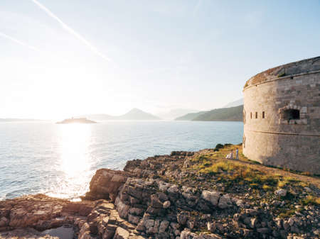 bride and groom are hugging near the Arza fortress on the Mamula islandの写真素材