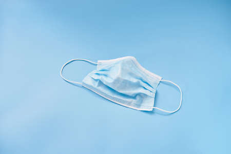 Isolated medical face mask on a blue background. Personal protective equipment.