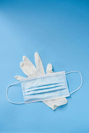 Isolated glove and face mask on a blue background. Protection during Covid-19 quarantineの写真素材