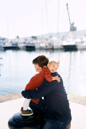Baby girl is hugging her daddy while having a family day by the seaの写真素材
