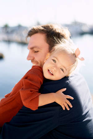 Father and daughter are hugging during their walk by the sea